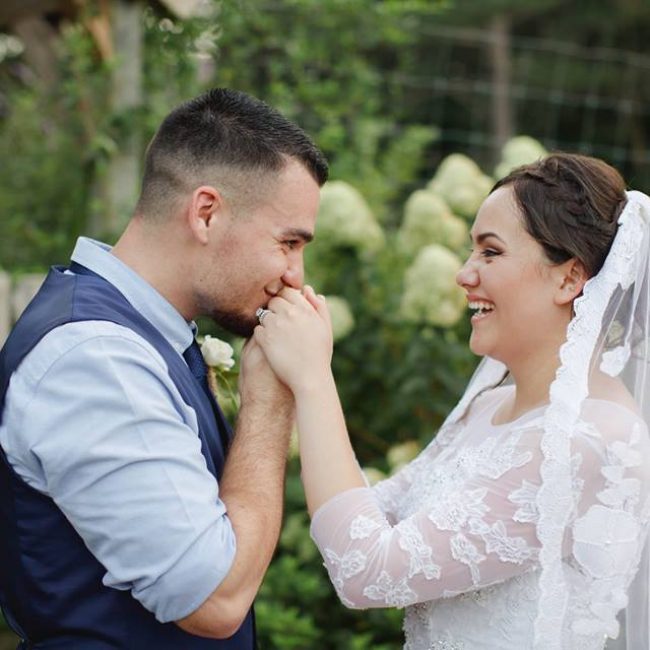 happy wedding coupe featuring man kissing the hands of his laughing bride