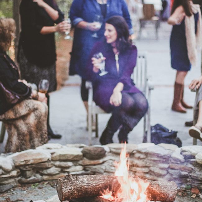 wedding reception detail shot of women drinking wine by the fire