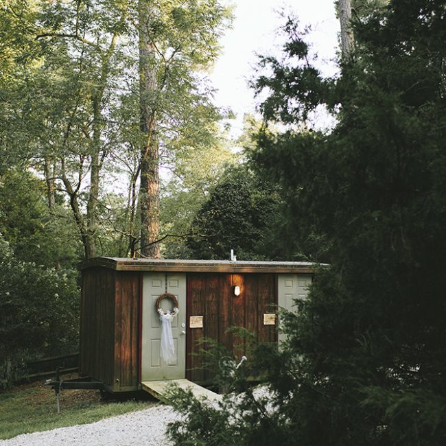 Outdoor wedding reception featuring restrooms tucked among trees